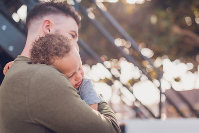 Baby leaning on dad's shoulder and dad hugging him