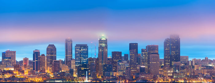 Illuminated buildings in city against sky