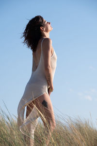 Young woman standing against sky