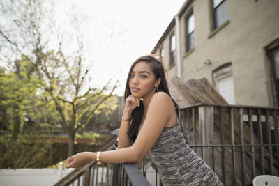 Young woman leaning on her balcony railing