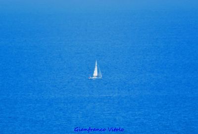 Sailboat sailing in sea against blue sky