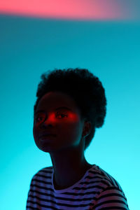 Young african american woman with neon red streak of light on face on vivid colorful background