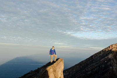 Man standing on mountain peak against sky