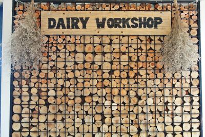 Dairy workshop text on metal grate against stack of firewood