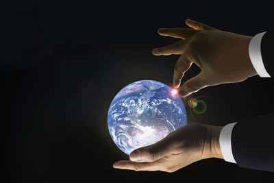 Close-up of hand holding umbrella against black background