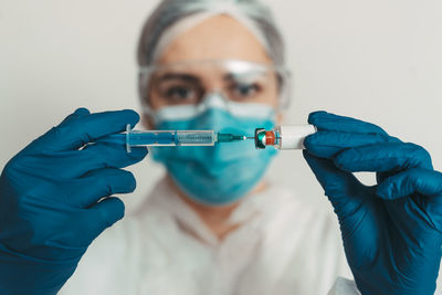 Portrait of man holding syringe against white backgrounds