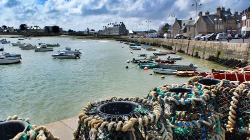 Boats at harbor against cloudy sky