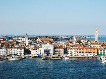 Aerial view of buildings by sea against clear sky during sunny day