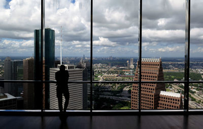 Man standing by railing in city against sky