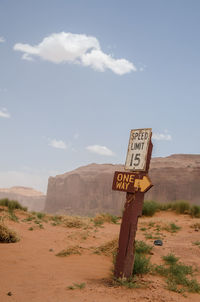 Information sign on sand against sky