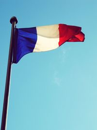 Low angle view of flag against clear blue sky