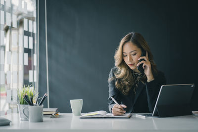 Young businesswoman using technology while working on table in office