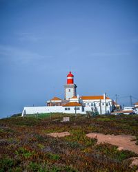 Lighthouse amidst buildings against sky