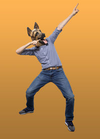 Full length of man jumping against orange background