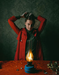 Portrait of young woman standing against wall