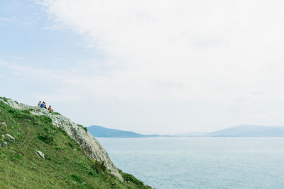 Scenic view of sea by mountain against sky