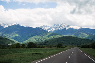 Road leading towards mountains against sky