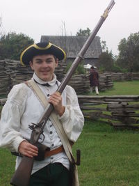 Portrait of boy wearing costume while holding rifle on field