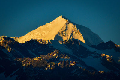 Scenic view of snowcapped mountains against clear blue sky