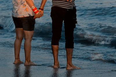 Low section of women standing on beach