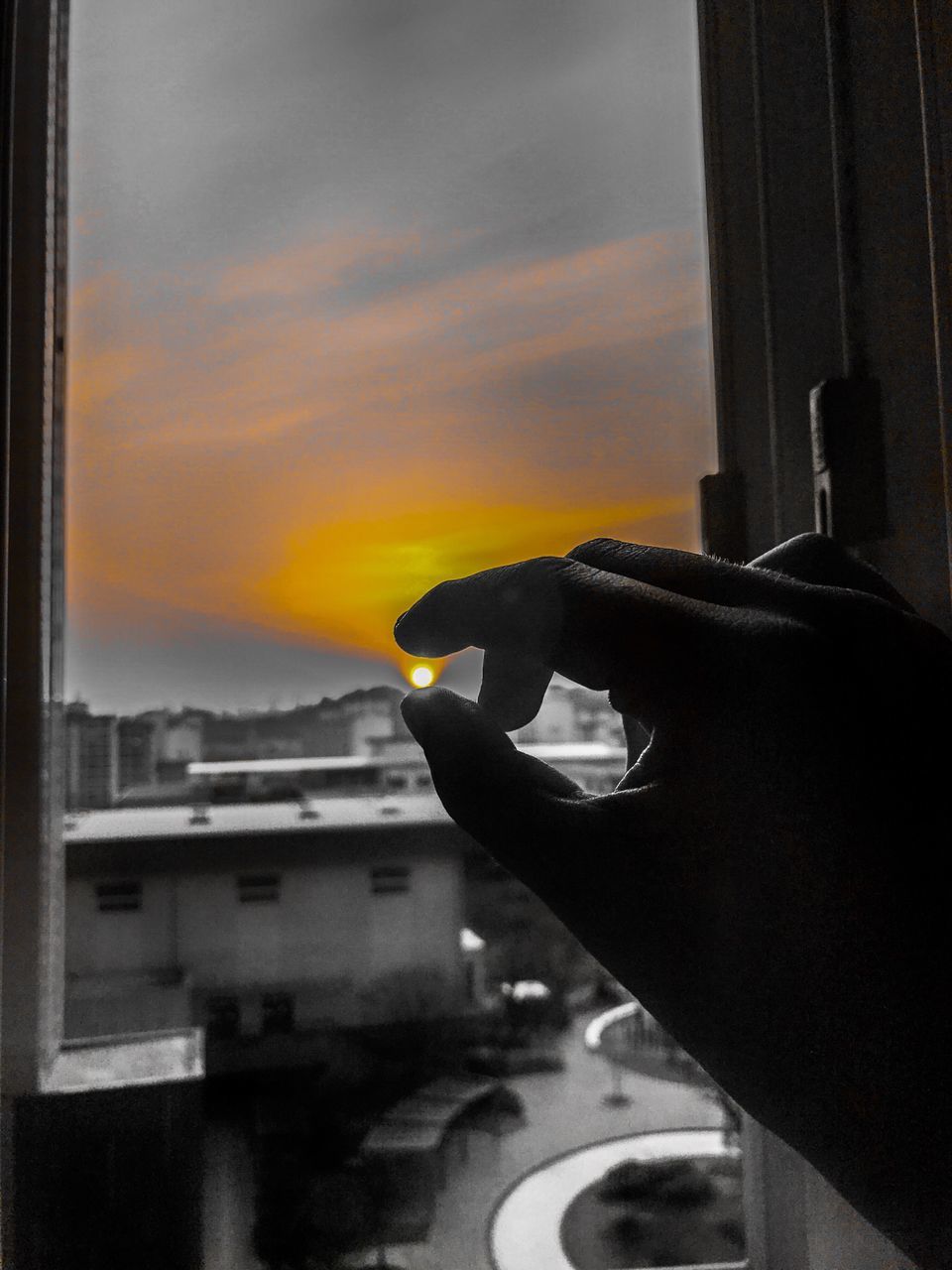 PERSON HOLDING GLASS WINDOW AGAINST SUNSET SKY