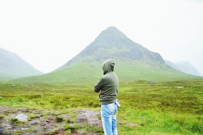Rear view of man standing on mountain against sky