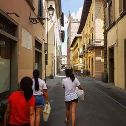 Rear view of people walking on street amidst buildings in city