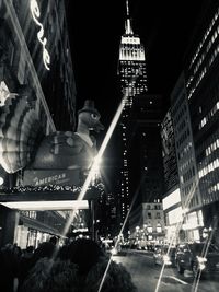 Illuminated street amidst buildings in city at night