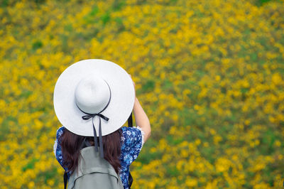 Rear view of woman standing against yellow flowering plants