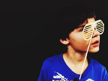 Boy holding novelty glasses over black background