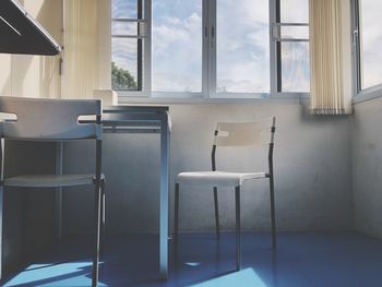 Empty chairs and table against window