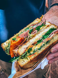 Close-up of hand holding cut toasted cheese sandwich 