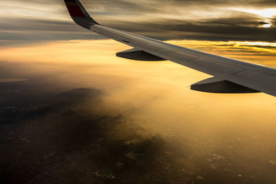 Close-up of airplane wing against sky during sunset