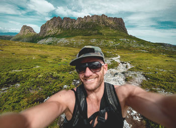 Portrait of smiling man wearing sunglasses against mountain