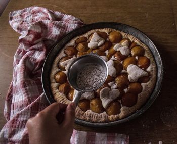 Cropped image of hand icing dessert on table