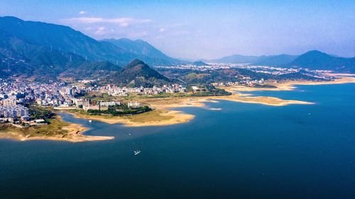 Aerial view of city by sea against sky