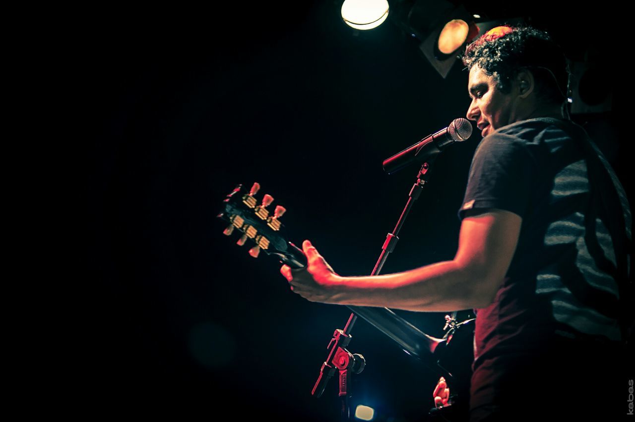 LOW ANGLE VIEW OF MUSICIAN PLAYING GUITAR AT NIGHT