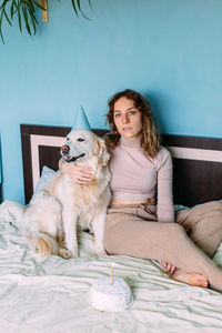 Full length of young woman sitting on bed