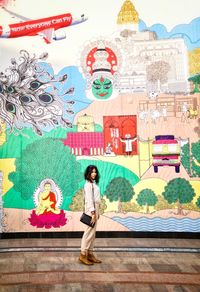 Full length of woman standing against multi colored wall