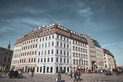 People walking on street against sky in city