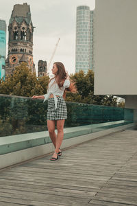 Young woman standing against buildings in city