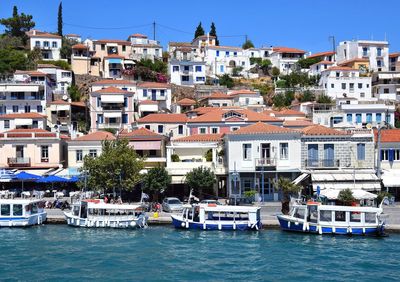 Sailboats moored in sea against buildings in city