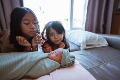 High angle view of mother and daughter sitting on bed at home