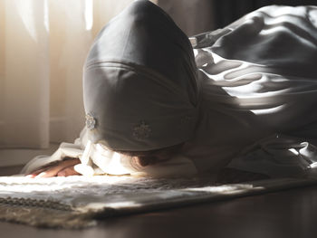 Low section of woman relaxing on bed at home