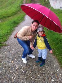 Portrait of mother holding umbrella standing with son 