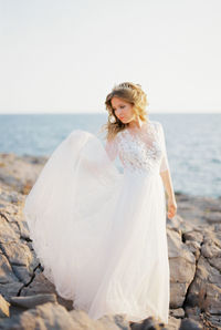 Portrait of smiling woman standing at beach against clear sky