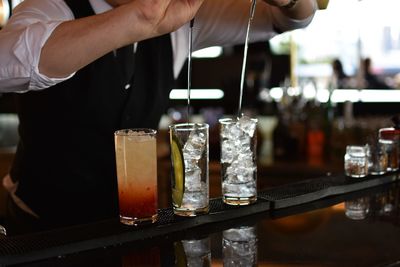 Midsection of man pouring liquid in drink at restaurant