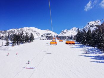 Ski lift over snow covered mountains against sky