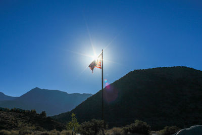 Low angle view of flag on mountain against clear blue sky