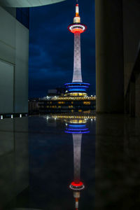 Illuminated tower in city against sky at night